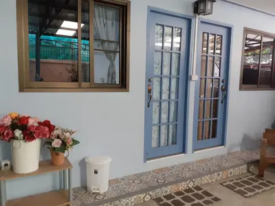 a house with blue doors and flowers on the floor at BaanSu Hostel in Bangkok
