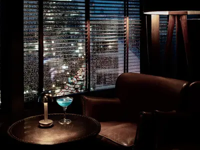 a drink on a table in front of a window at MUU Bangkok, Small Luxury Hotels of the World in Bangkok
