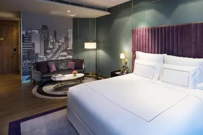a bedroom with a large bed and a living room at MUU Bangkok, Small Luxury Hotels of the World in Bangkok
