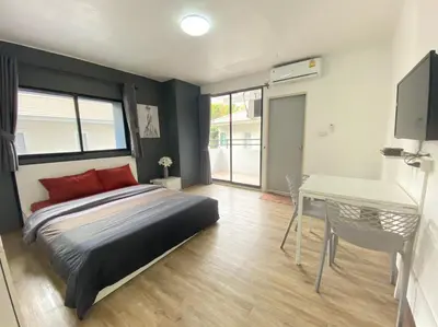 a bedroom with a bed and a table and a desk at Baansuay Rattanathibet Apartment in Nonthaburi