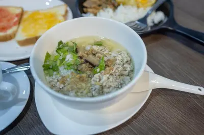 a bowl of soup on a white plate with food at Baansuay Rattanathibet Apartment in Nonthaburi