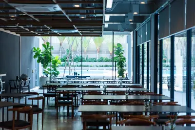 a dining room with tables and chairs and windows at Reno hotel in Bangkok