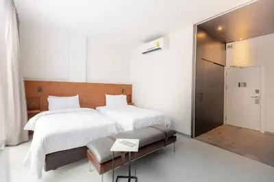 a bedroom with two beds and a bench in it at Reno hotel in Bangkok