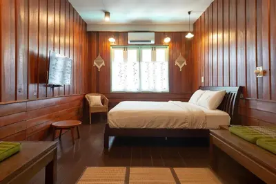 a bedroom with a bed with wooden walls and a window at Home & Hashery Boutique House in Bangkok