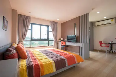 a bedroom with a bed and a desk and a television at Live at Home Sukhumvit 105 in Bangkok