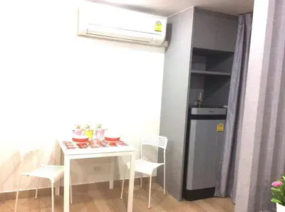a small kitchen with a table and a refrigerator at Live at Home Sukhumvit 105 in Bangkok