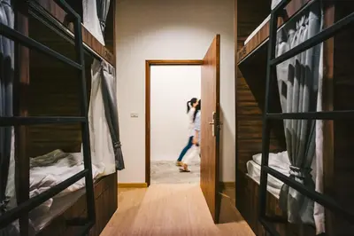 a woman walking through a room with bunk beds at Hostel Urby in Bangkok