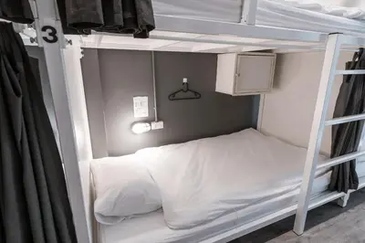 a bedroom with a bunk bed with white sheets at The Cocoon Hostel in Bangkok