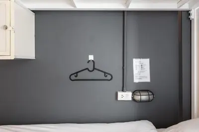 a bedroom with a blue wall with a hanger and a bed at The Cocoon Hostel in Bangkok