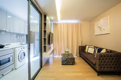 a living room with a couch and a kitchen at Dazzle Residence in Bangkok