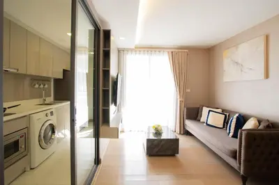 a small living room with a couch and a kitchen at Dazzle Residence in Bangkok