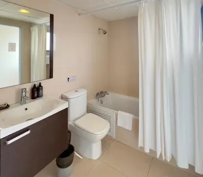a bathroom with a toilet and a sink and a bath tub at BU Place Hotel in Bangkok