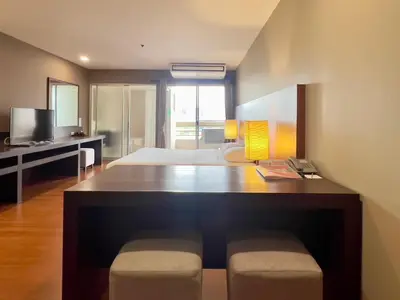 a room with a large desk with a bed and a bedroom at BU Place Hotel in Bangkok
