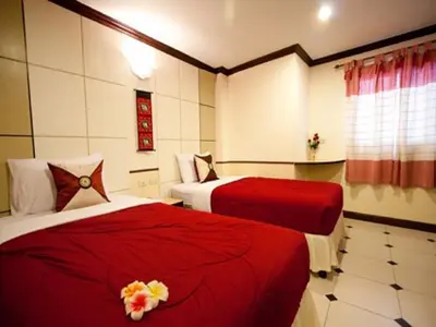 two beds in a hotel room with red sheets at Honey House 2 in Bangkok