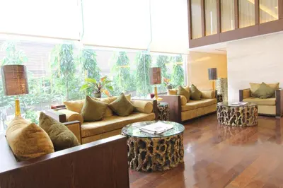 a living room with couches and tables and a large window at Jasmine Resort Bangkok in Bangkok