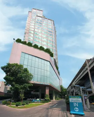 a tall pink building with a tree in front of it at Jasmine Resort Bangkok in Bangkok