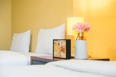 a vase with a pink flower on a table in a bedroom at The Corner Ratchada in Bangkok