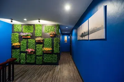 a hallway with a green wall with flowers and plants at The Corner Ratchada in Bangkok