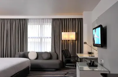 a hotel room with a bed and a couch and a television at Best Western Sukhumvit 20 in Bangkok