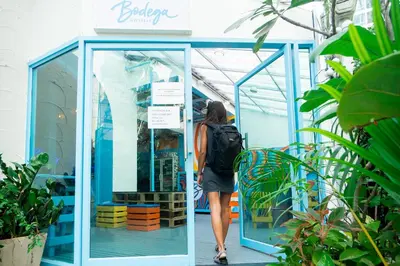 a woman with a backpack walking through a glass door at Bodega Bangkok Soi 23 in Bangkok
