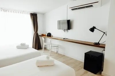 a hotel room with two beds and a desk at Varmtel in Bangkok