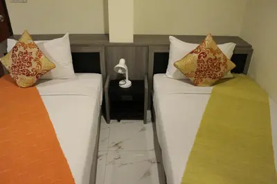 two beds with pillows and a table with a clock at Samsen Sam Place in Bangkok