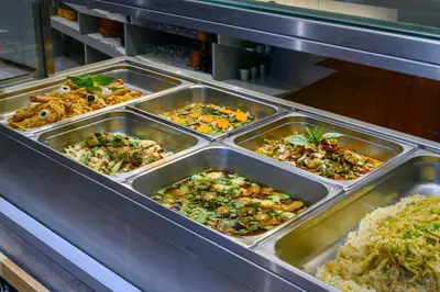 a buffet line with trays of different types of food at VELA be Bangkok Ratchathewi in Bangkok