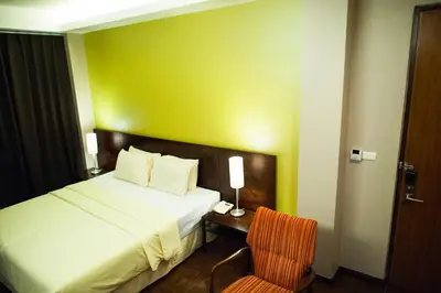 a hotel room with a bed and a chair at Baansilom Soi 3 in Bangkok