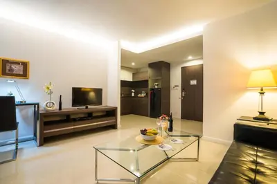 a living room with a glass coffee table and a television at Beyond Suite in Bangkok