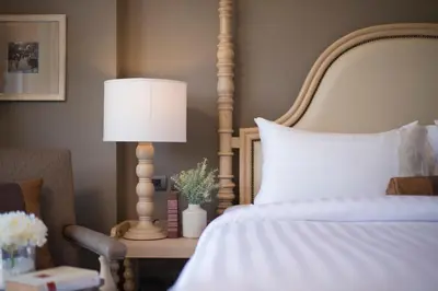 a bedroom with a bed with a lamp and a chair at Casa Vimaya Riverside in Bangkok