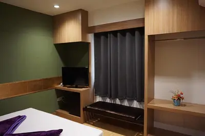 a bedroom with a bed and a tv and a window at Kaya Place in Bangkok