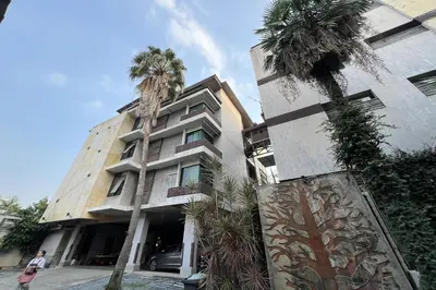 a building with two palm trees in front of it at Eurna Resort Hotel in Bangkok