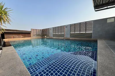 a swimming pool with blue tiles in front of a building at Eurna Resort Hotel in Bangkok
