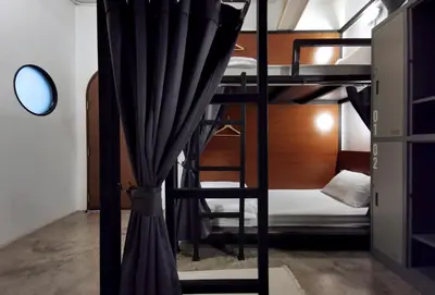 a bunk bed with a curtain in a room at Apartment45 Hostel in Bangkok