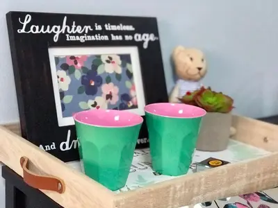 two green cups on a shelf with a picture and a teddy bear at Nesto Condo at Muangthong in Pak Kret