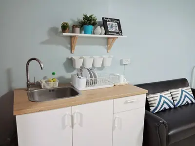 a kitchen counter with a sink and a couch at Nesto Condo at Muangthong in Pak Kret