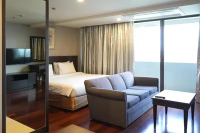 a hotel room with a bed and a couch at Royal Suite Hotel Bangkok in Bangkok