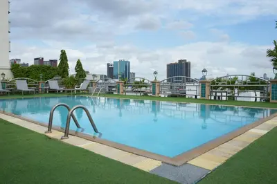 a large swimming pool with a city in the background at Royal Suite Hotel Bangkok in Bangkok