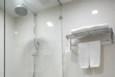 a shower with white towels and a shower head at Royal Suite Hotel Bangkok in Bangkok
