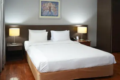 a bedroom with a large white bed with two lamps at Royal Suite Hotel Bangkok in Bangkok