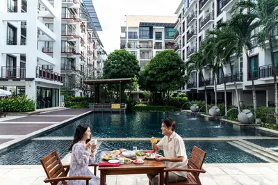two people sitting at a table in front of a pool at Amanta Hotel & Residence Ratchada in Bangkok