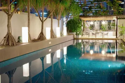 a swimming pool with palm trees in a building at Park Plaza Bangkok Soi 18 in Bangkok