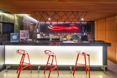 a bar with red stools in front of a counter at Park Plaza Bangkok Soi 18 in Bangkok