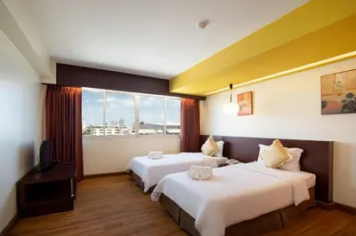 a hotel room with two beds and a large window at Veronica Residence in Bangkok