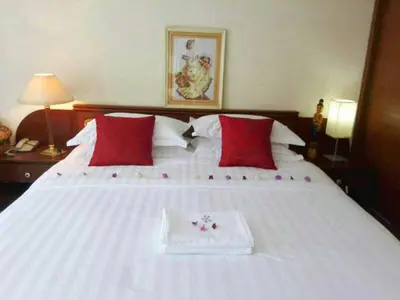 a white bed with red pillows and a tray on it at Poonchock Mansion in Bangkok