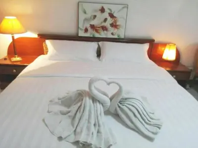 a white bed with a heart shaped towel on it at Poonchock Mansion in Bangkok