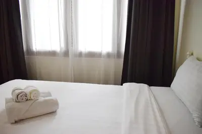 two towels on a white bed with a window at Greenery Hostel in Bangkok