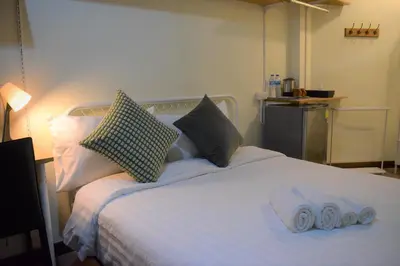 a white bed with two rolled up towels on it at Greenery Hostel in Bangkok