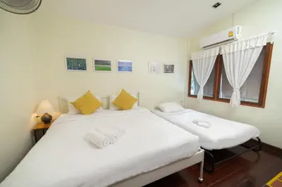 two twin beds in a room with a window at Greenery Hostel in Bangkok