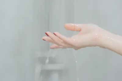 a woman washing her hands in front of a mirror at Peace Factory Hostel in Bangkok